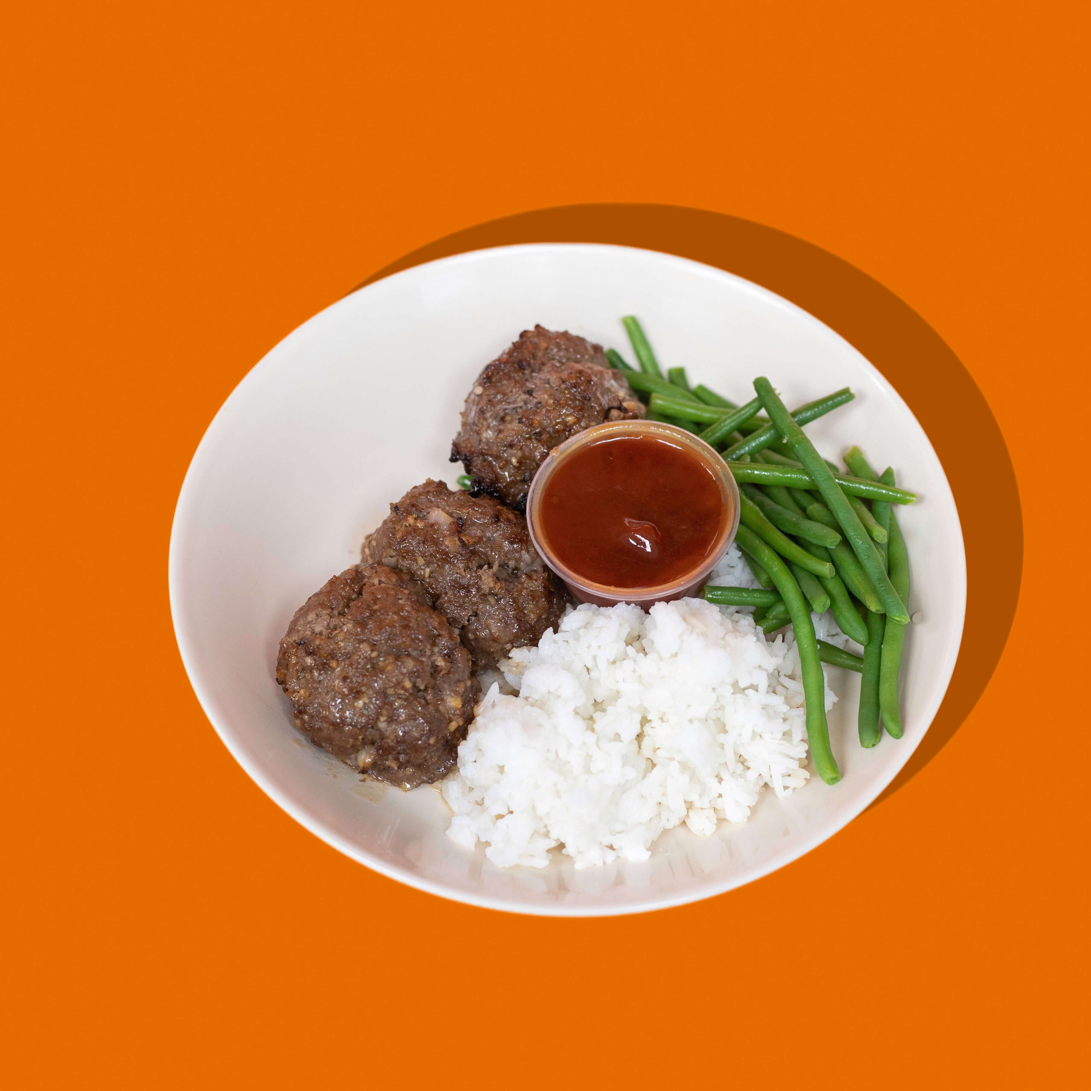 Boulette de bœuf style pain de viande de BigMig présentée sur une assiette blanche, accompagnée de légumes colorés et de sauce, illustrant un repas sain, nourrissant et équilibré.