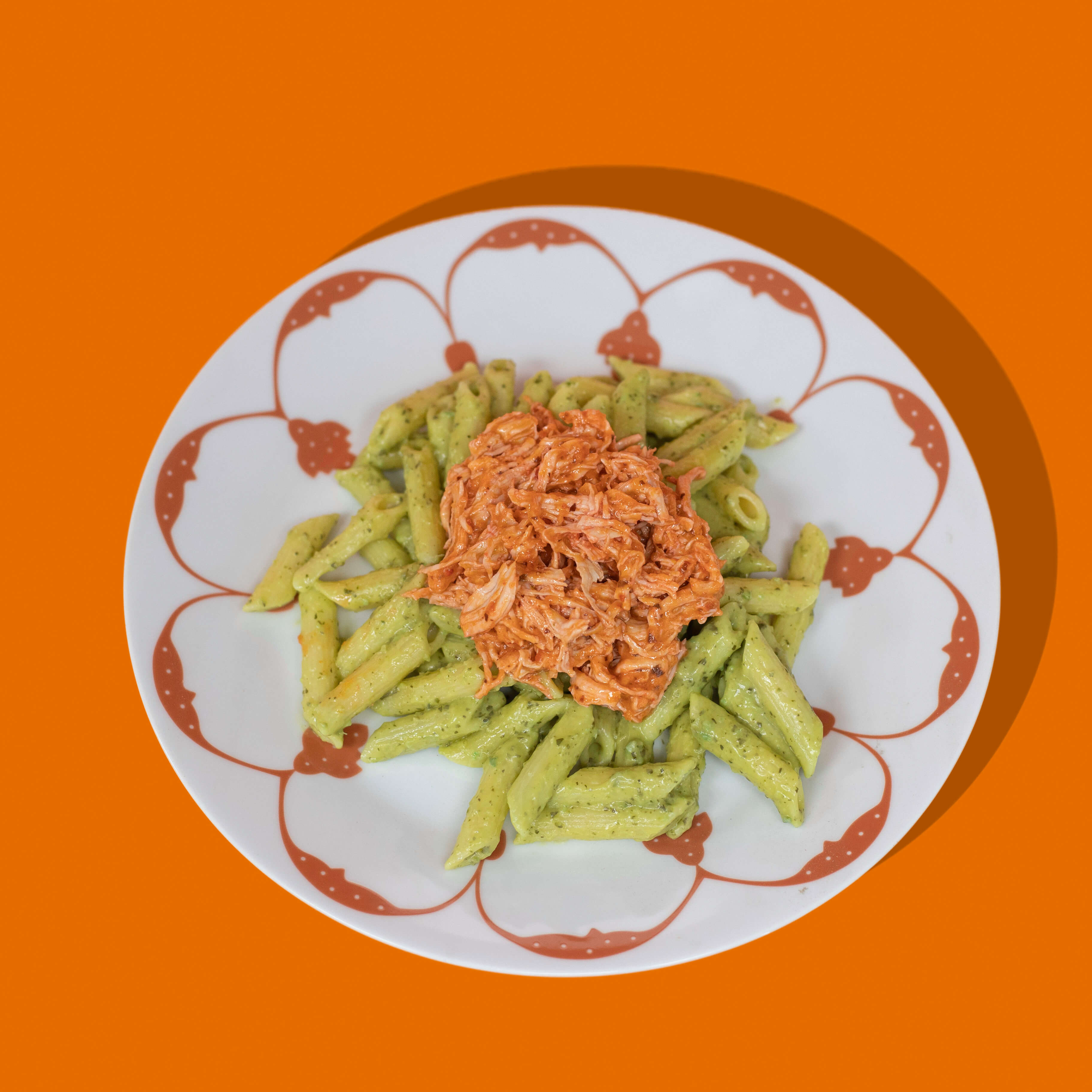 Penne aux deux pestos de BigMig servies dans une assiette blanche, encore meilleur garnies de basilic frais et de copeaux de parmesan, illustrant un plat de pâtes gourmand et savoureux. 