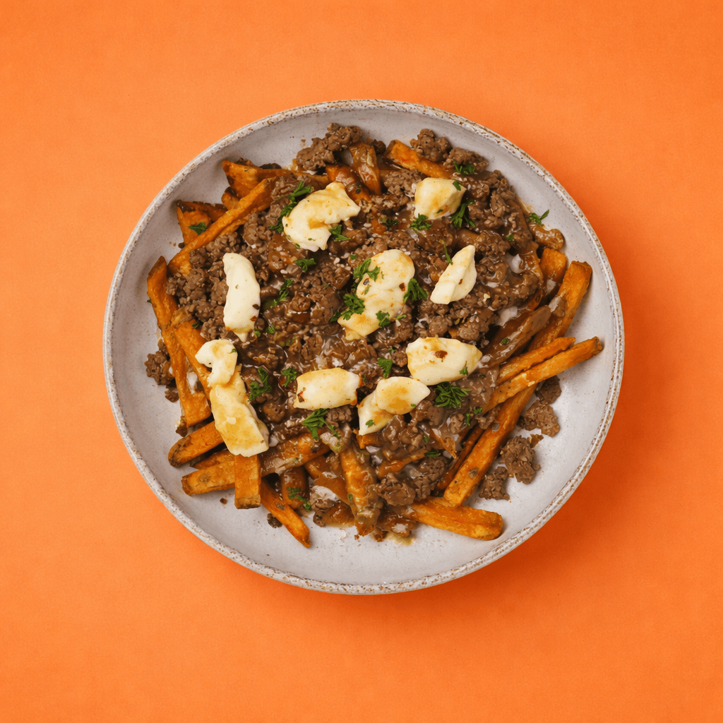 Poutine revisitée avec frites de patates douces garnies de bœuf haché, fromage en grains fondant et sauce brune, présentée en vue du dessus sur fond orange uni avec éclairage studio et ombre nette.