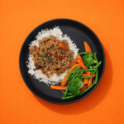 Une assiette noire mate contient du riz blanc, un sauté aux poivrons et oignons, accompagné de légumes verts (brocoli, haricots verts) et de carottes. Bigmig prêt-à-manger sans gaspillage